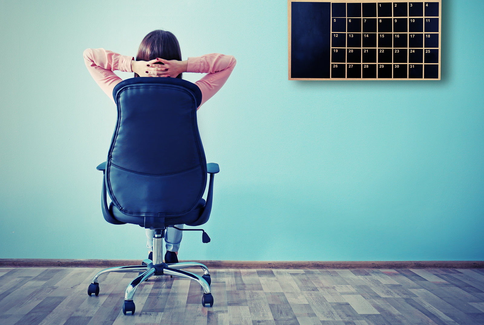 Woman sitting back on the office chair and looking at chalkboard Coach : productivité personnelle